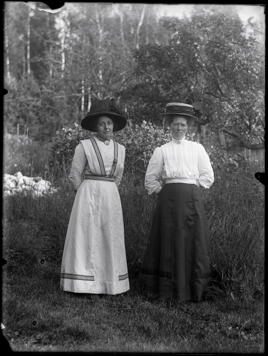 Två okända kvinnor i moderiktiga hattar