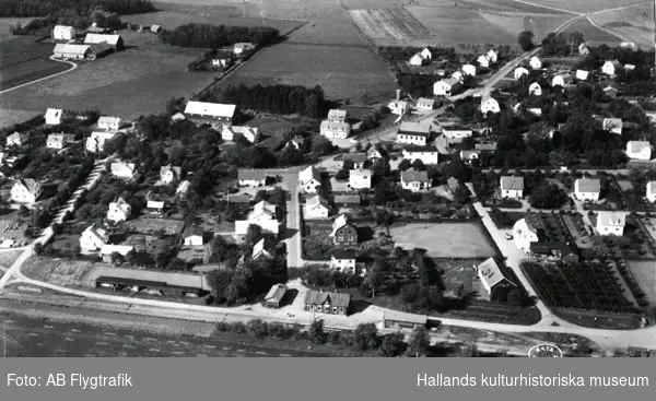 Vykort med flygbild över Vinbergs stationssamhälle med "Pyttebanan", Falkenbergs järnväg, och dess station i förgrunden. Enfamiljshus och trädgårdar. Lantgårdar. Byvägar, skog och odlingslandskap.