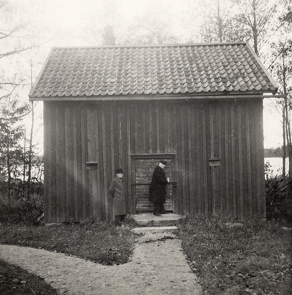 Två äldre män står utanför en ekonomibyggnad i Sjösås hembygdspark, 1937.