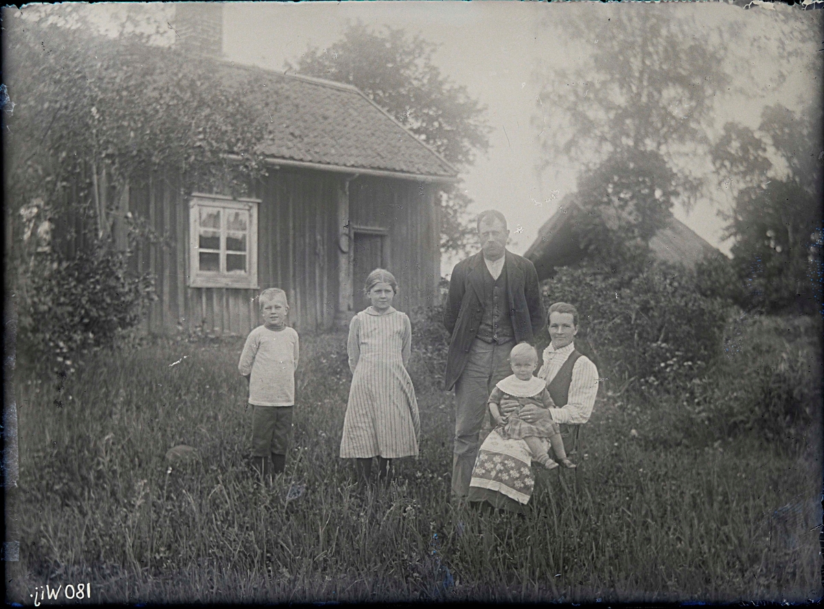 Fotografering beställd av E. A. Holm. Föreställer sannolikt Karl August Holm (1875-1953) och hans hushållerska Albertina Amalia Johansdotter (1875-1955) med deras gemensamma barn Märta Ingeborg (1906-1995), Oskar Vilhelm (1909-1970) och Karl Evert (1916-1983).