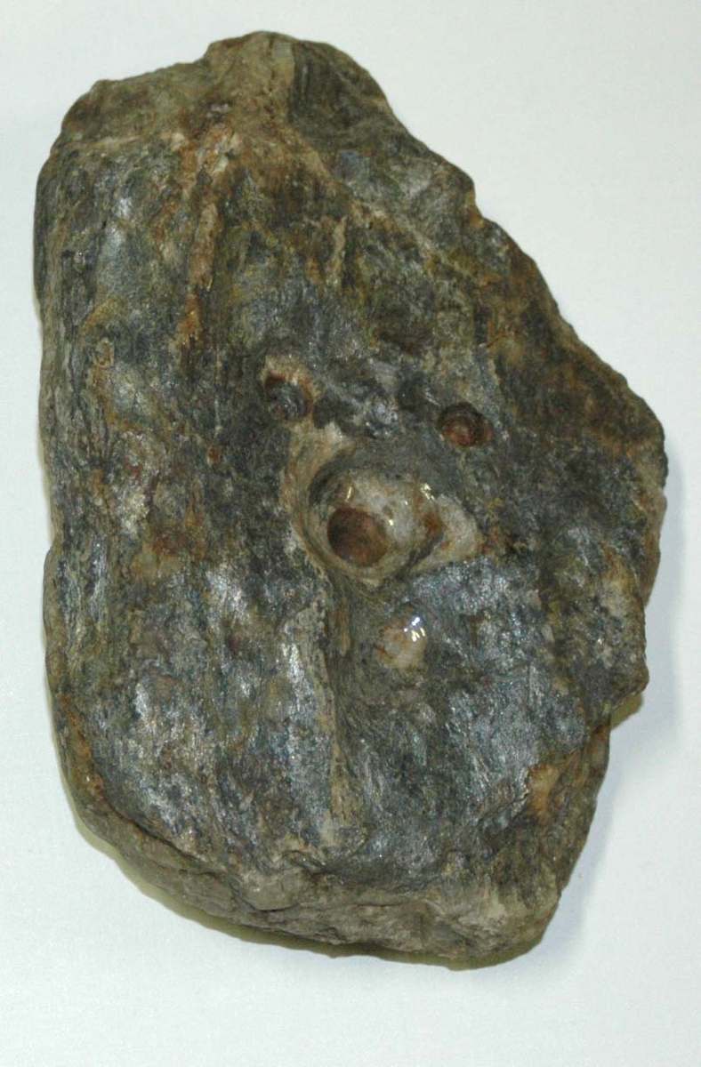 Flat stein, litt trekantet og avrunded i formen, med hull på den ene siden.