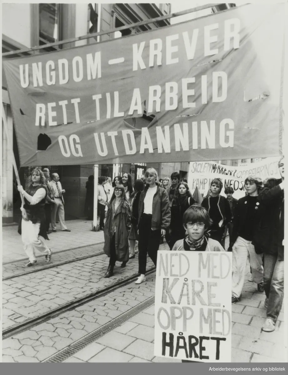 1. mai 1983, Oslo. På transparent: Ungdom krever- rett til arbeid og utdanning. På plakat: Ned med Kåre opp med håret.
