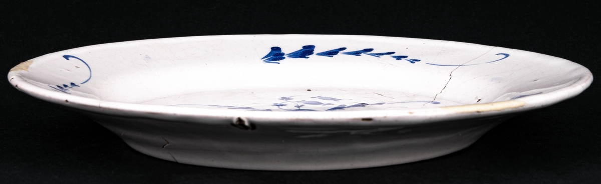 Assiett av fajans, vit med blå ornering, Signerad "MB"=Marieberg.
