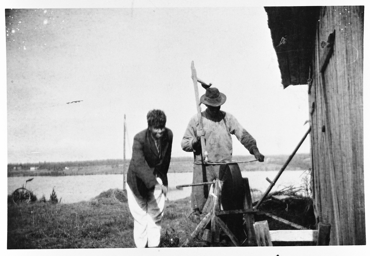 Rasmussveen på Eina, Vestre Toten, 1918. Rasmus J. Amlie sliper ljåen, mens Magnus Amlie drar slipesteinen.