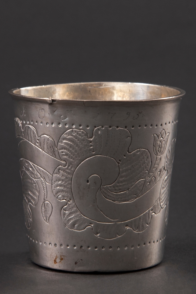 Beger i sølv med svakt konisk form. Korpus er dekorert med punslet og gravert stilisert rankedekor.