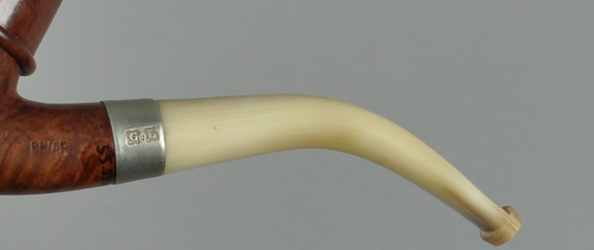 Pipe av briar med munnstykke av bein eller horn. Mellom pipehode og munnstykke er det en holk av stål.