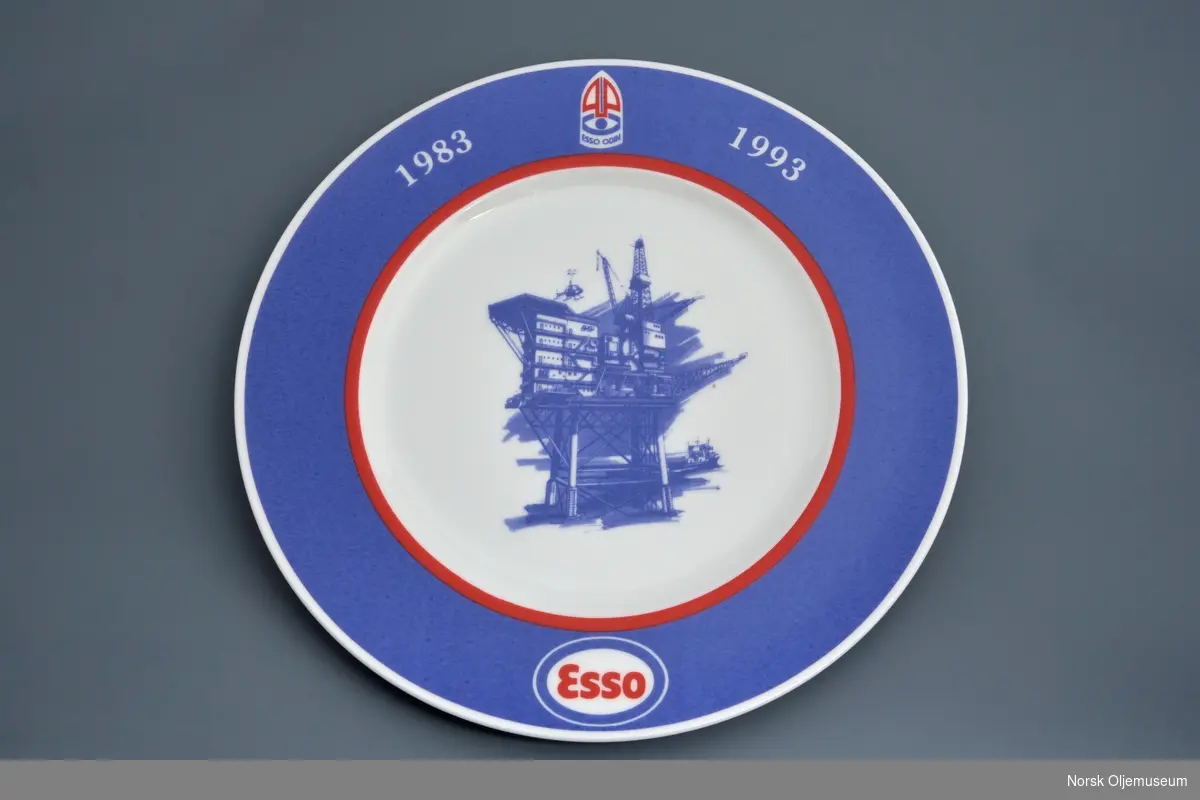 Jubileumsplatte dekorert med logo for Esso og illustrasjon av oljeplattform.