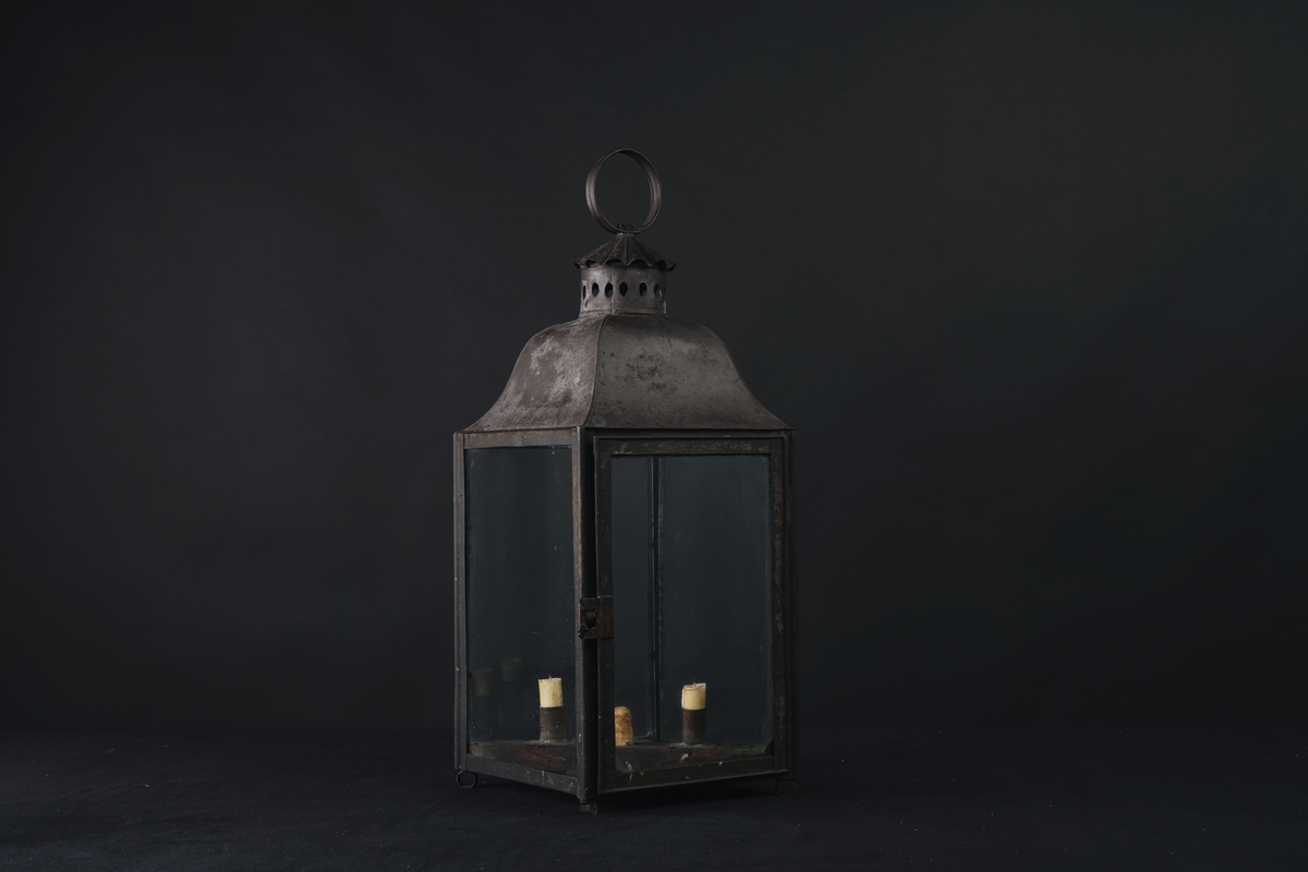 Brunmålad lykta, avsedd för tre ljus. Fyrkantig.
Användes av arbetsgrupperna IP och IH vid arbete i Gamla Dockan, ÖVK, under 1800-talet.