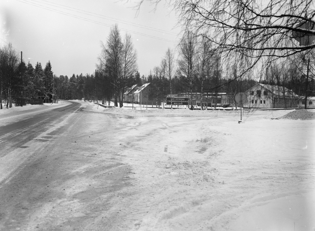 I en vägkorsning i Mullsjö står en skylt med texten AB Svenska Charmeuseväveriet Mullsjö.