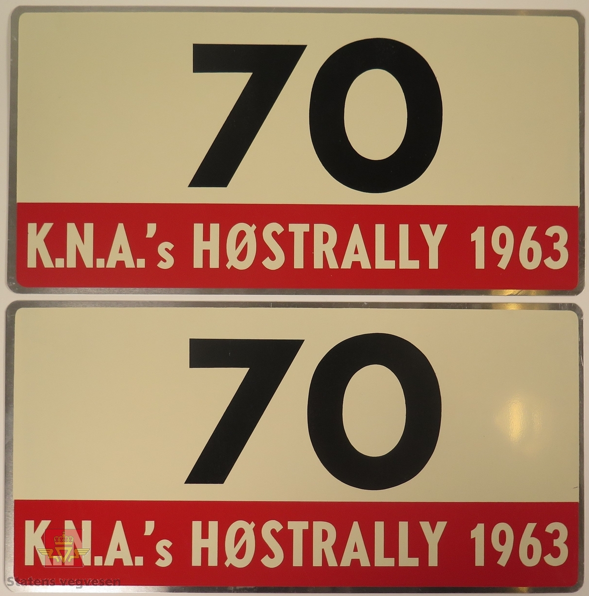Hovedsakelig hvite metallskilt med et mindre rødt markeringsområde. Grupperingen med skilt har også nummeret "70" påført seg, dette er en indikasjon på deltakernummer.
Påskrift: K.N.A.'s HØSTRALLY 1963