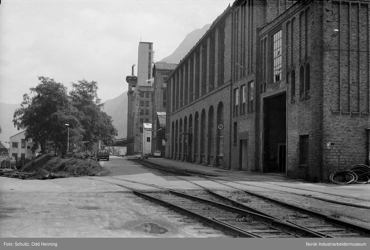 Materiallagerets utvendige fasade og jernbanespor på fabrikkområdet.