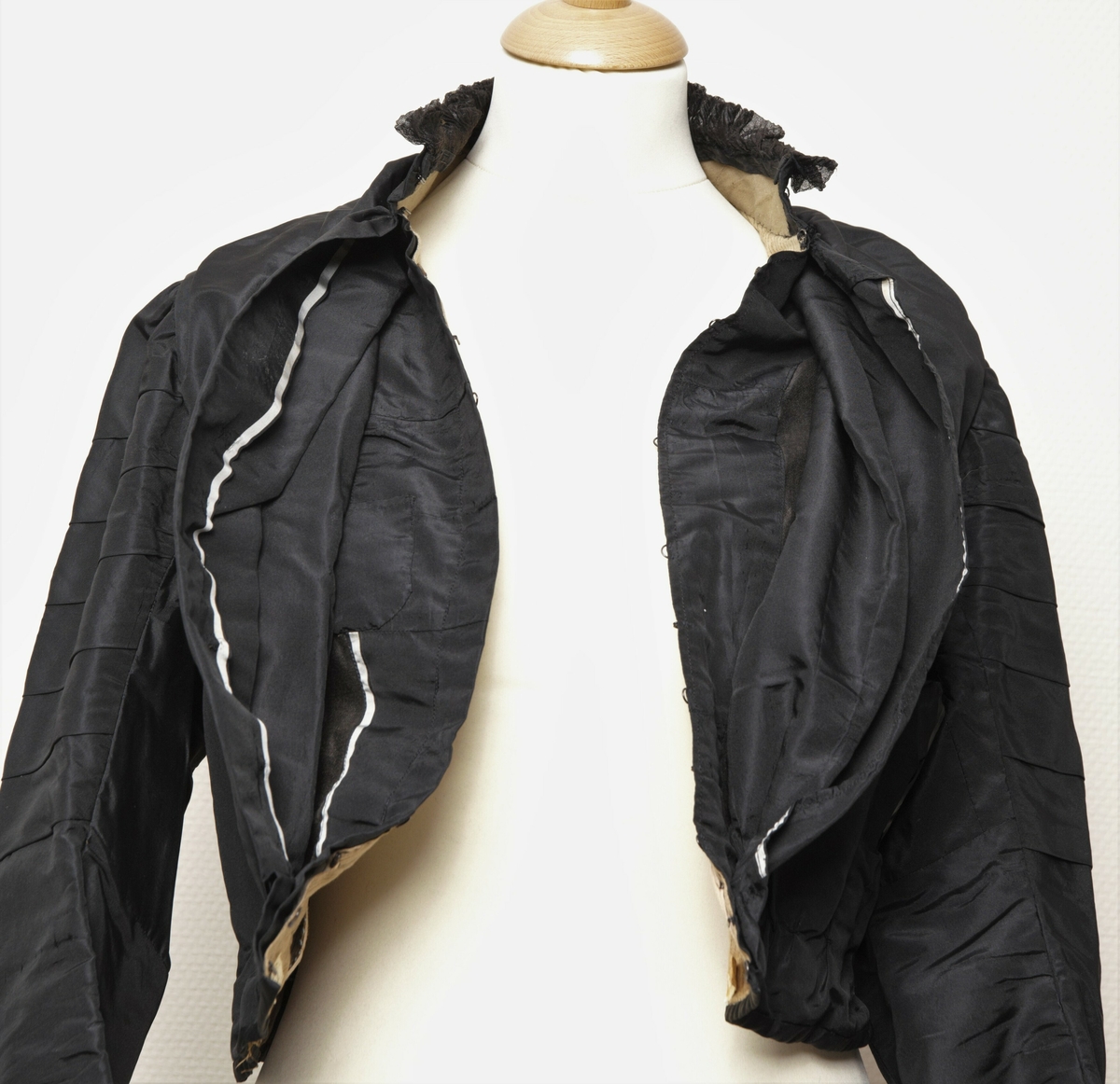 Kvinnetrøye eller kjoleliv sydd i svart silketaft. Med isydde spiler. Dobbel lukking foran. 