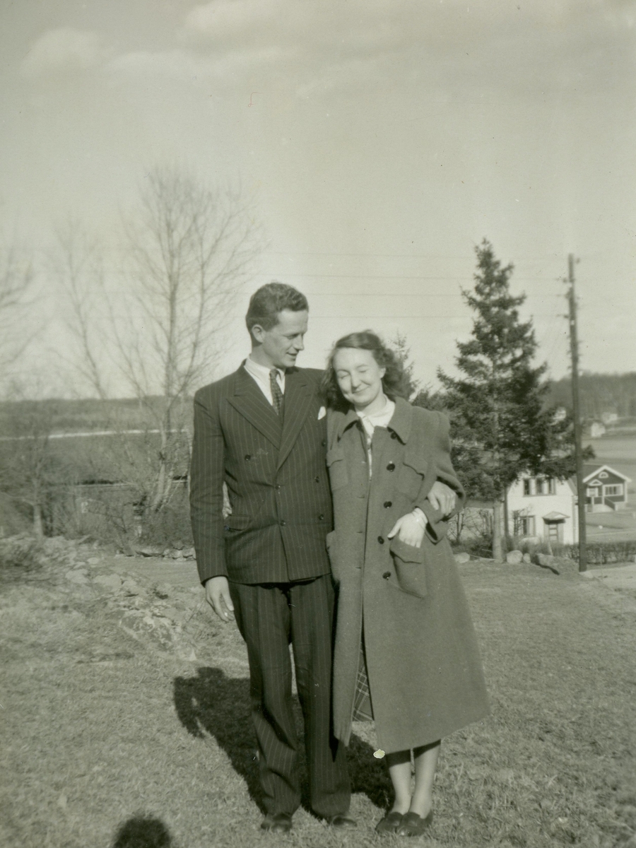 Björn Ekman (1913 - 1992) och Mary Ekdahl (1920 - 1988, gift Ekman) står i Labacka vid Missionskyrkan (senare Ekenkyrkan), 1 maj 1941. Till höger ses bröderna Magnussons bostäder "Villa Altuna" (Heljeredsvägen 1) och "Villa Soltorp" (Heljeredsvägen 3). Relaterat motiv: A2850.