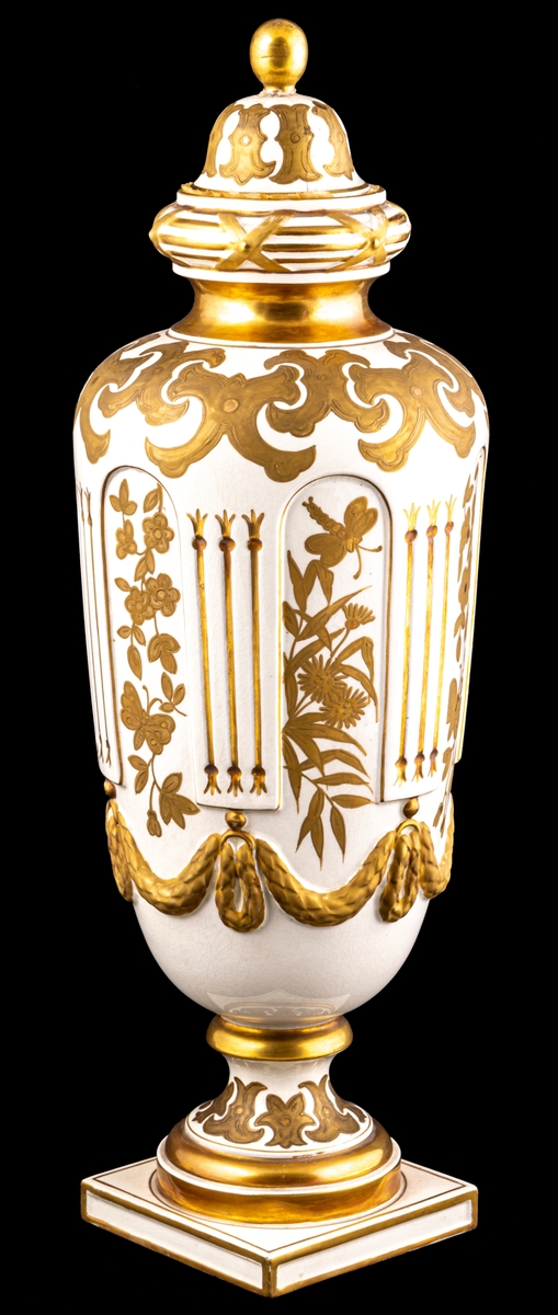 Urna av porslin med gustaviansk dekor i form av blommor och blad med girland. Dekoren är förgylld och bronserad. Försedd med lock med förgylld knopp. På undersidan av foten står Gustafsberg 1894. 
Stämpel: ankare.