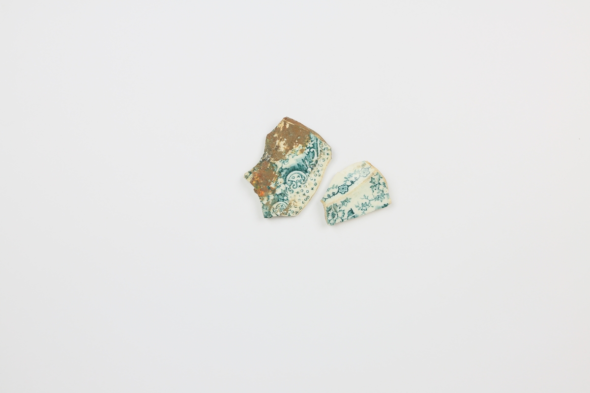 To fragment av porselen med turkist/blått blomster- og havdekor.