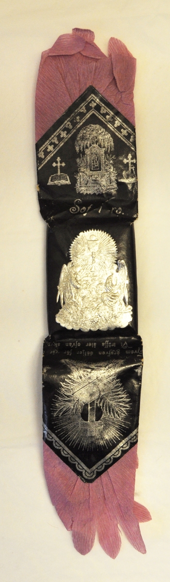 Rektangulär karamell inslagen i svart silkespapper som är krusat i ändarna. På framsidan finns ett präglat bokmärke förställande Jesus i beige färg. Skadat papper på ena sidan.