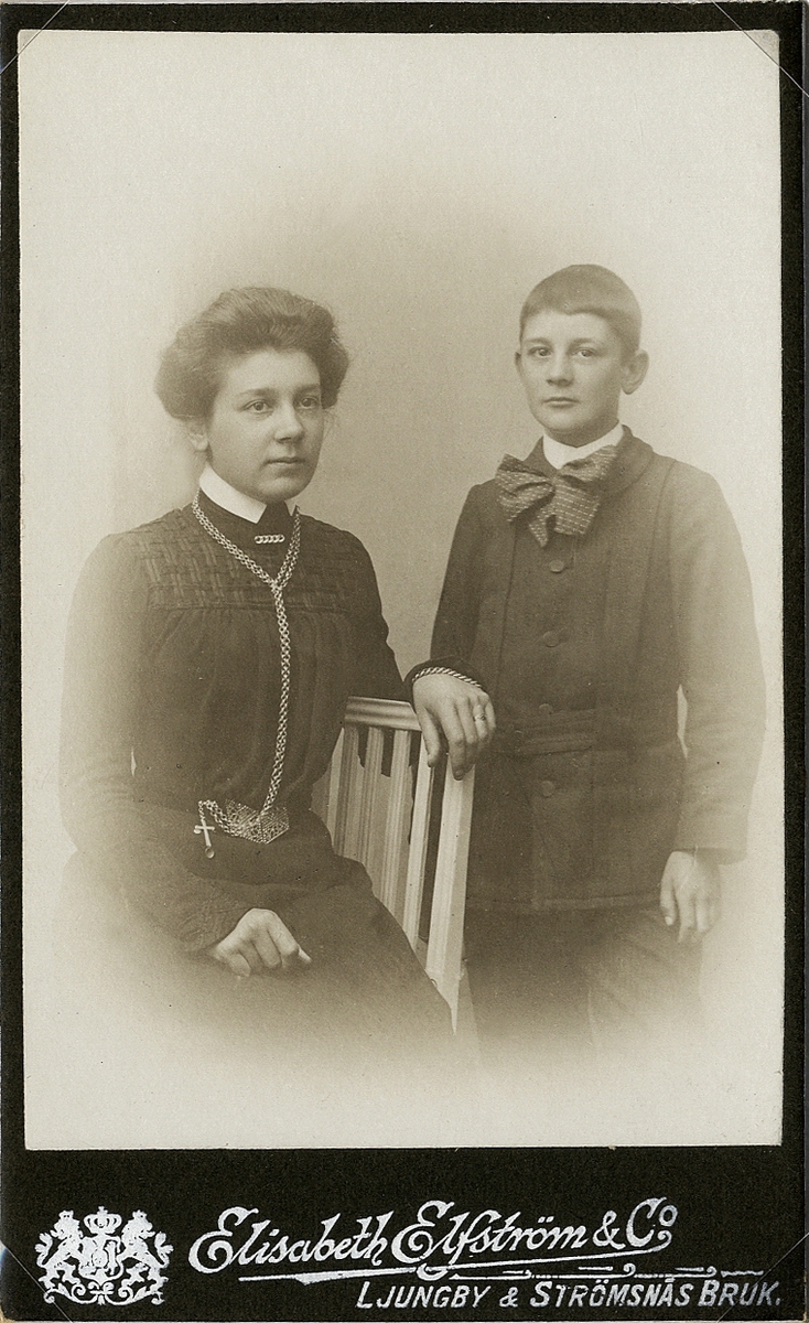 Ateljéfoto av två syskon, Eufrosyne ("Effa") Meijer och Carl Axel Meijer.
Knäbild, halvprofil. Ljungby, ca 1900.