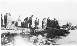 Bagasje lastes i nordlandsbåt ved steinkai. Mange personer p