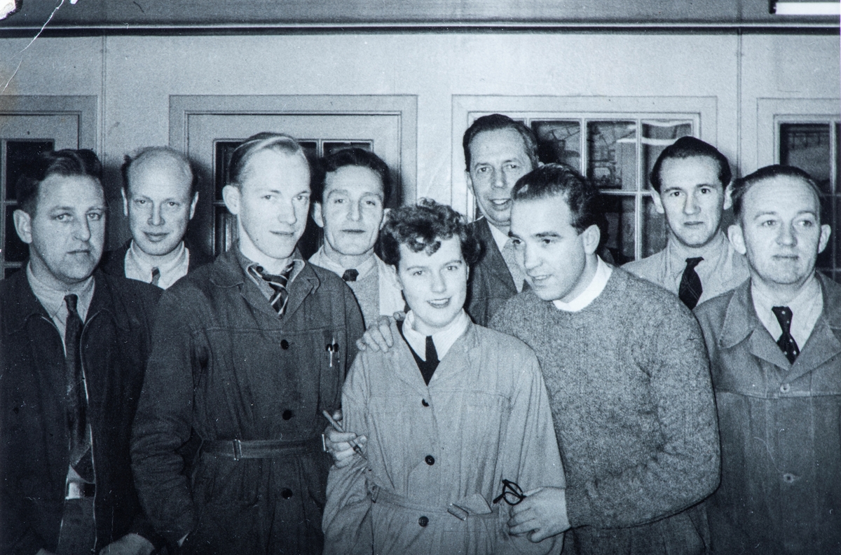 Gruppe 9 arbeidere, ved Hamar Jernstøperi på 1950-tallet. Ham-Jern. Kledd i arbeidsfrakk.  nr 3 fra venstre er Kåre Bekkelien, nr 6 er Einar Johansen, som ble kalt fr EJO. nr 8 er Yngve Jørstad, resten er ukjente.