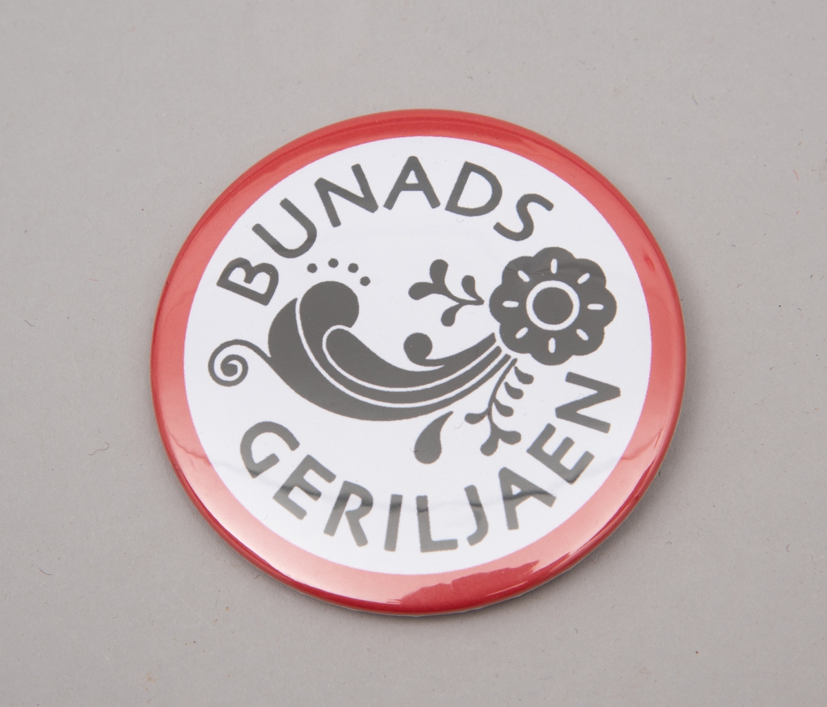 Buttons med påskrift "Bunadsgeriljaen" og logo-motiv i rødt, hvitt og sort.