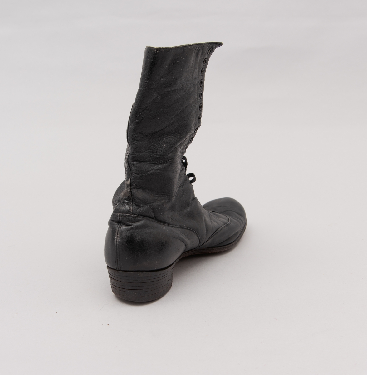 Et par damestøvler i sort lær med snøring. Laget av AS Raade skofabrikk, Moss.