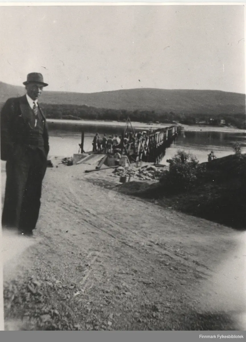 En ukjent mann står ved siden en bukkebru som går over Tanaelva, bygget av pionerkompaniet, 1939.