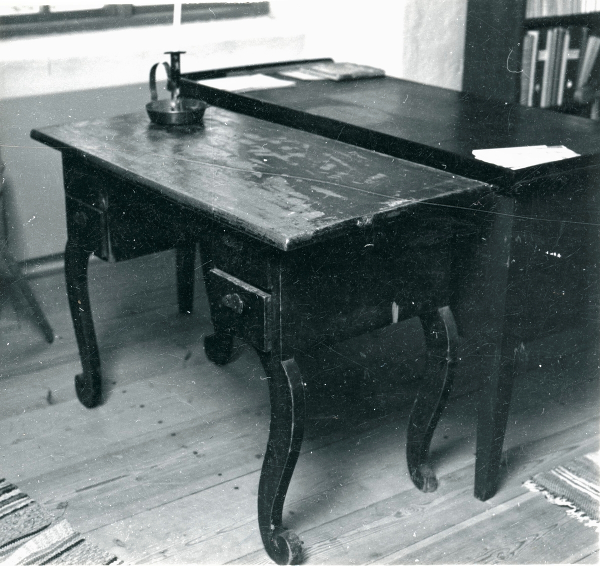 Skrivbord med svart skiva, i övrigt rödmålat. S-formiga ben och fem lådor, två på vardera sidan och en i mitten. Nyckelskyltar i läder.