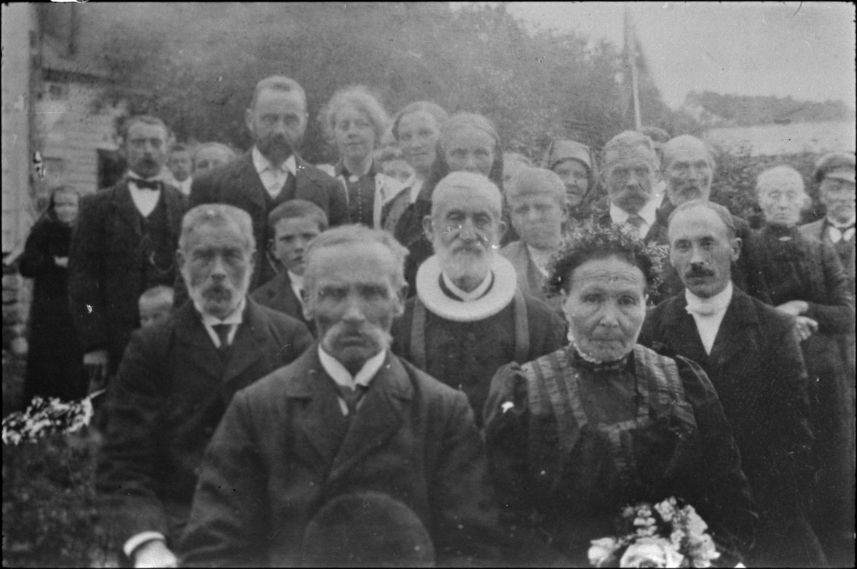 Bryllaupslaget til kyrkjetenar Kolbein Haugland og Inger Kristine Skjold i Ølen, 26. juli 1915. Presten de Seuv og klokkaren E. Einarsen sit bak brudeparet.
