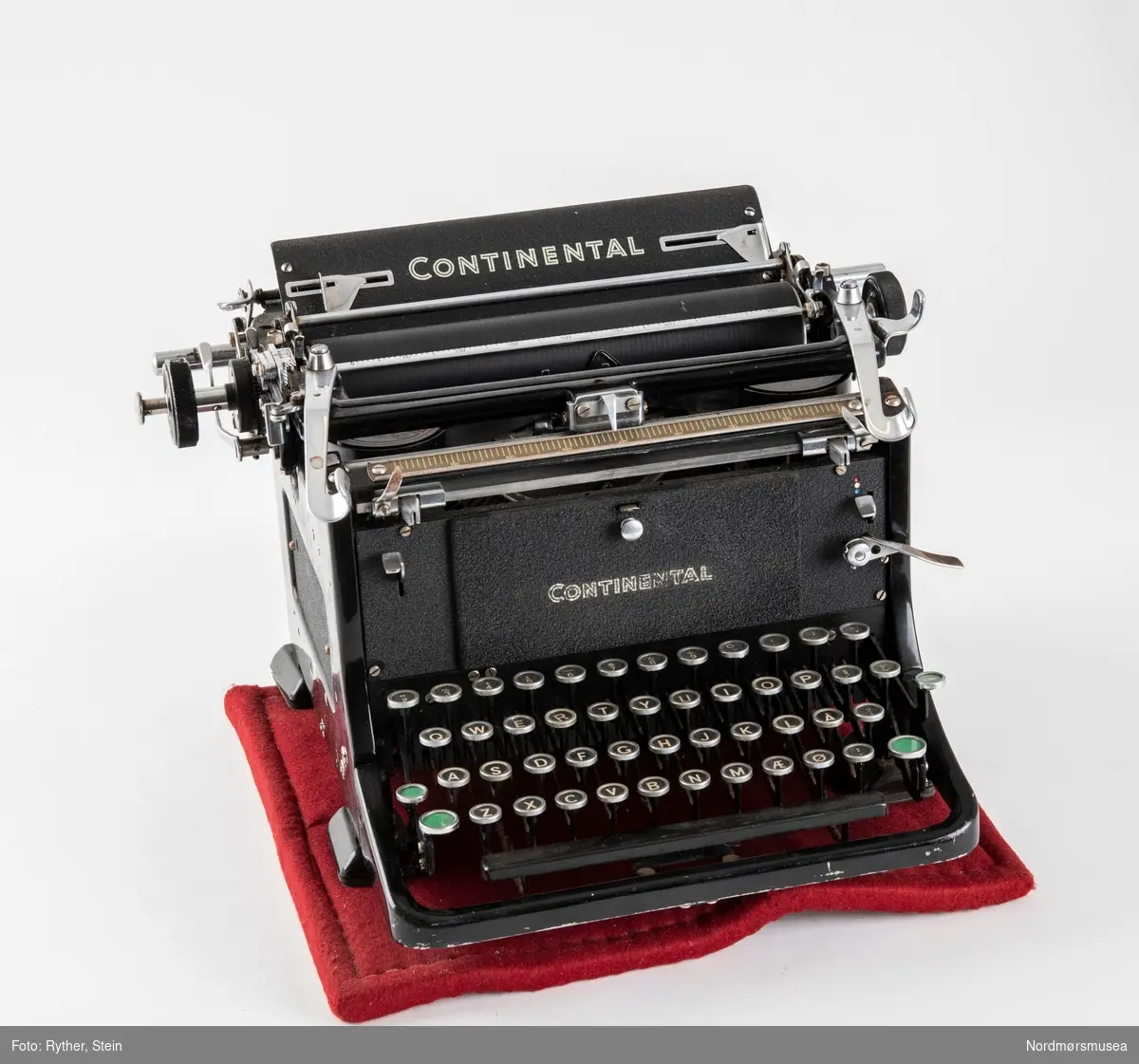Continental Standard skrivemaskin fra 1951/52. Medfølger underlag med gummibunn og rød filt på toppen. Dekke i plast.