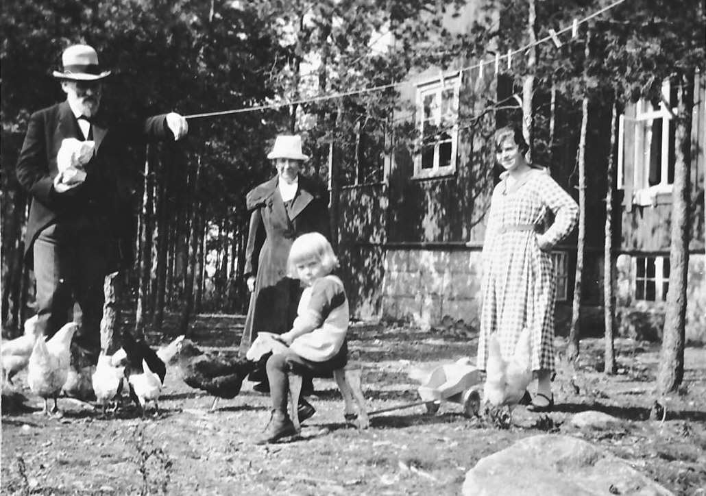 J. B. Bull mater høner, i selskap med dame og lita jente med lekehest og vogn. 
