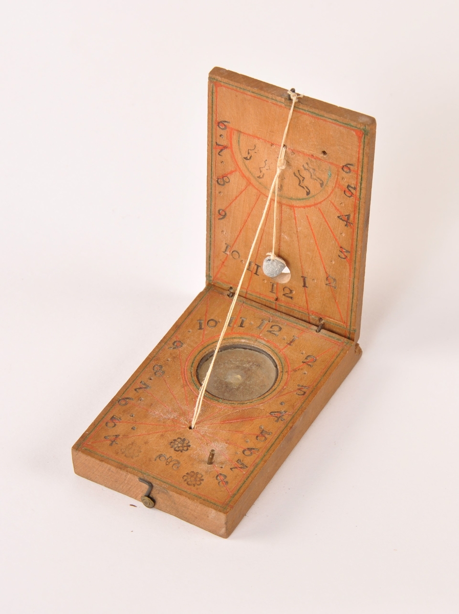 Solur med kompass i lommeformat, laget i tre, glass og metall. Tråd med blyperle viser tiden, påmalte streker for klokkeslett.