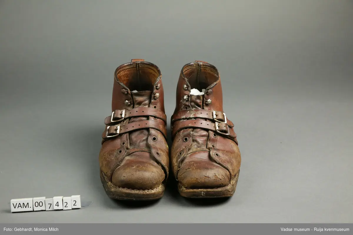 Brune beksøm/ storsko/ vintersko. Skoene bærer preg av å være godt brukt. Skoene kan tilpasses foten ved hjelp av lisser og reimer. Lissene er borte.