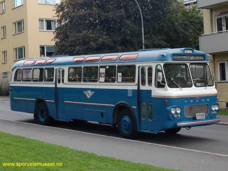 Buss i en mørk blå farge i nedre del, hvitt rundt vinduer og en lys blå farge på tak. Bussen har dører ved sjåfør i front og en i midten. 