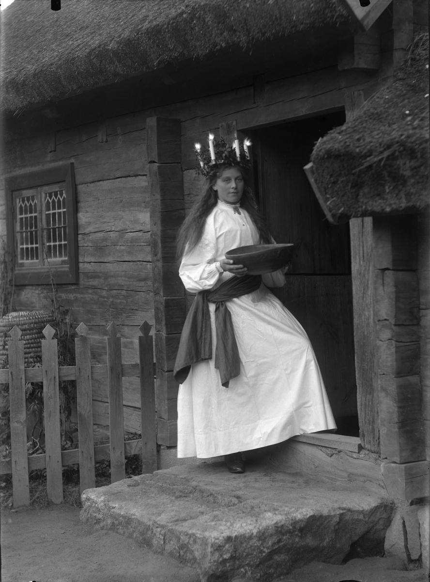 Lucia på Skansen. Kerstin Olsdotter från Mora som lucia utanför Oktorpsgården på Skansen 1899.