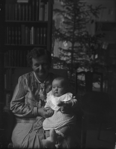 Kvinna med baby i knät framför julgran. Västerås.