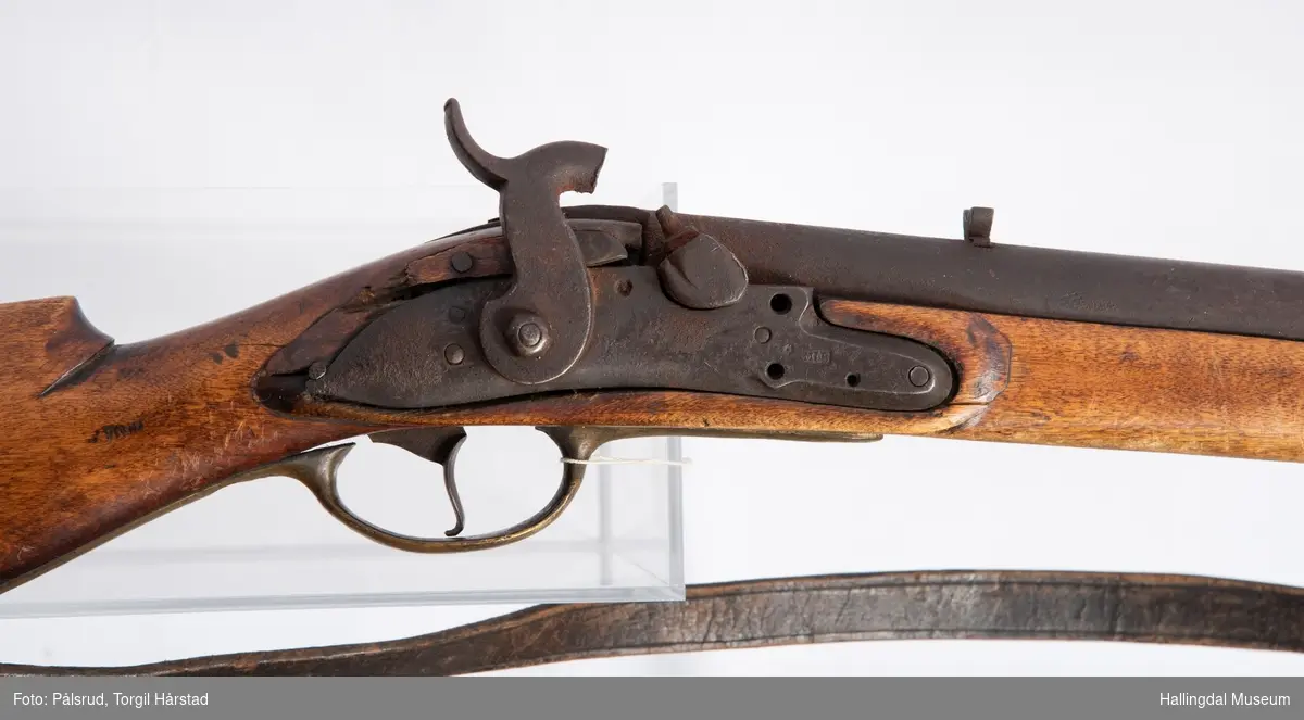 Gevær, modell fra 1769 - 1793, som er ombygd fra flintlås til perkusjonslås. Vært brukt av "Norske Gevorbne Jeger Corps" og senere av soldat nr. 90 i "Telemarkske Nationale jeger Corps Westenfjeldske Compani" i perioden 1818 - 1839. Geværet mangler kolbekappe, men har antatt original reim i brunt lær med messingknapp. Ladestokk i tre.
