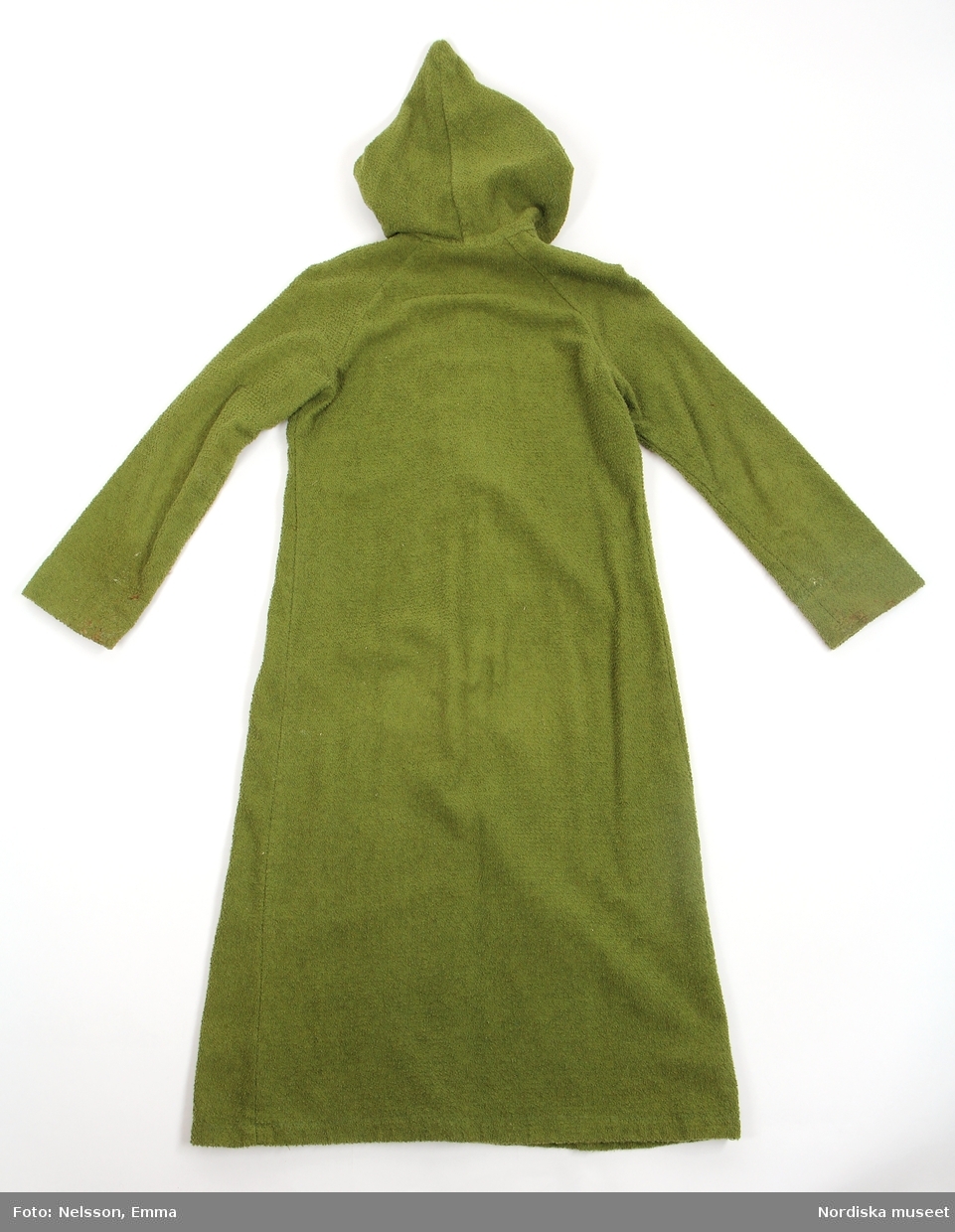 Katalogkort:
"Morgonrock av grön frotté. Utställd modell med huva och långa ärmar. Dragkedja från halslinning till 36 cm från fåll."
