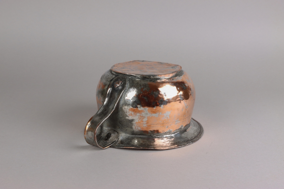 Copper chamber pot, plain circle form with flat base, angled rim above domed base with s-scroll handle. The pot shows traces of tin lining in the pot, on the handle and on the sides.