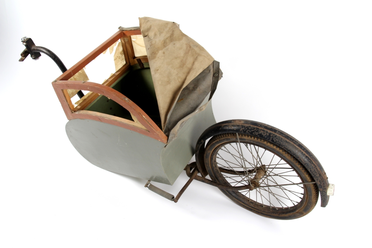 Sykkelvogn på ett hjul og med fjæring. Vognen har vinduer og plass til ett barn.