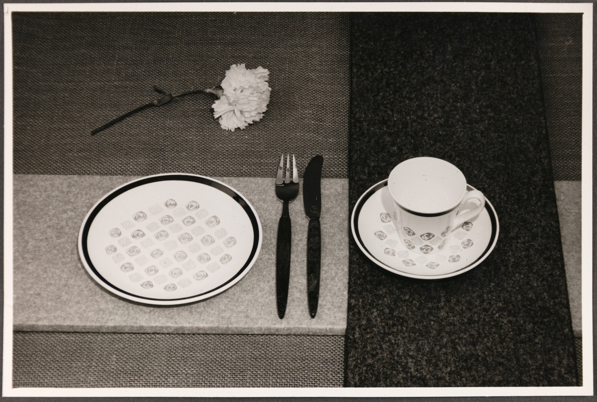 Frokostserviset "Mosaikk" fra Stavangerflint A/S. Avbildede objekter viser en tallerken, kopp med underskål, sukkerskål og bordoppdekning med kniv og gaffel. 
