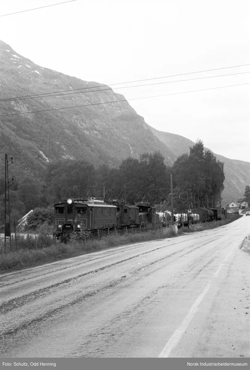 Tog med flere lokomotiv og vogner på Rjukanbanen, ved jernbaneovergangen på Dale.