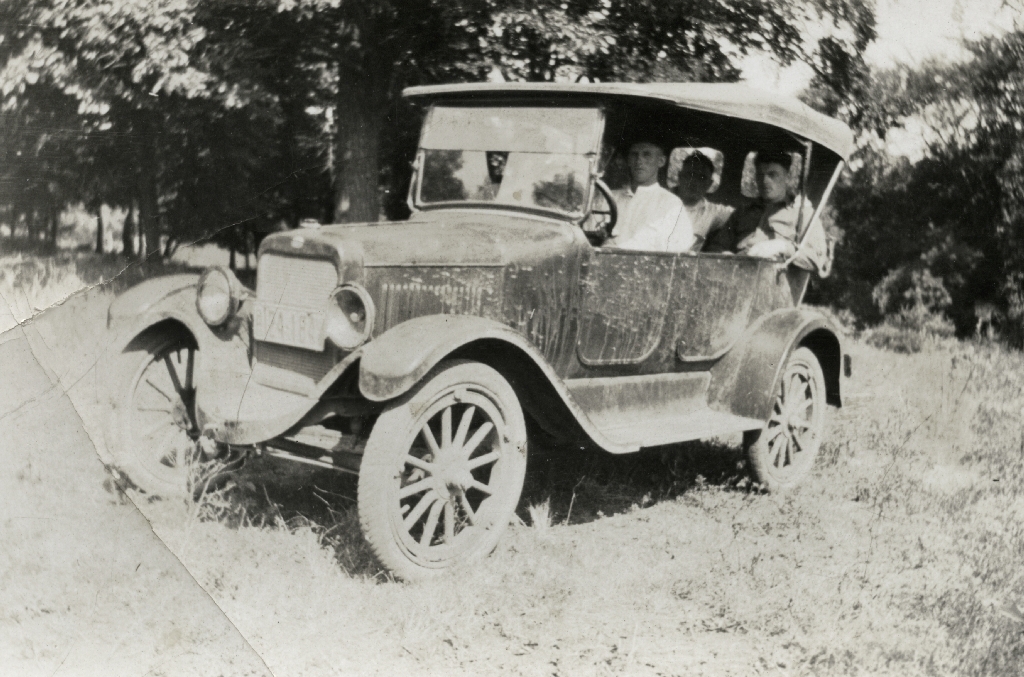 En bil med unge menn inni står på en gressbakke.