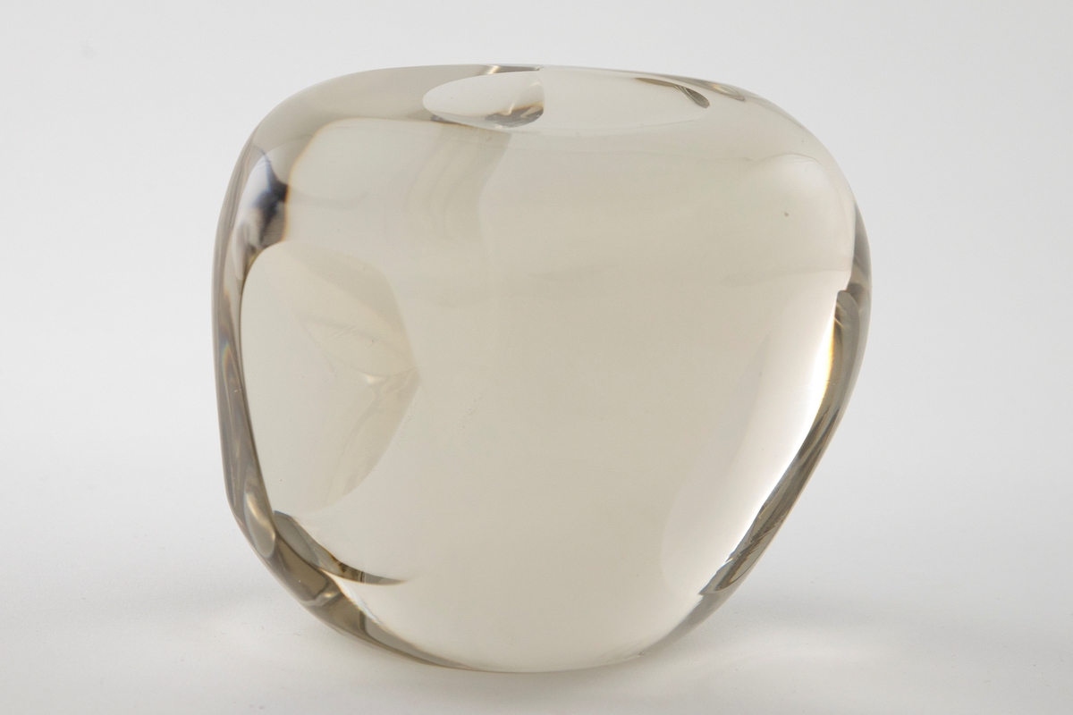 Irregulær kuleformet skulptur av massiv klart glass med slipte ovalformede og runde partier på yttersiden.