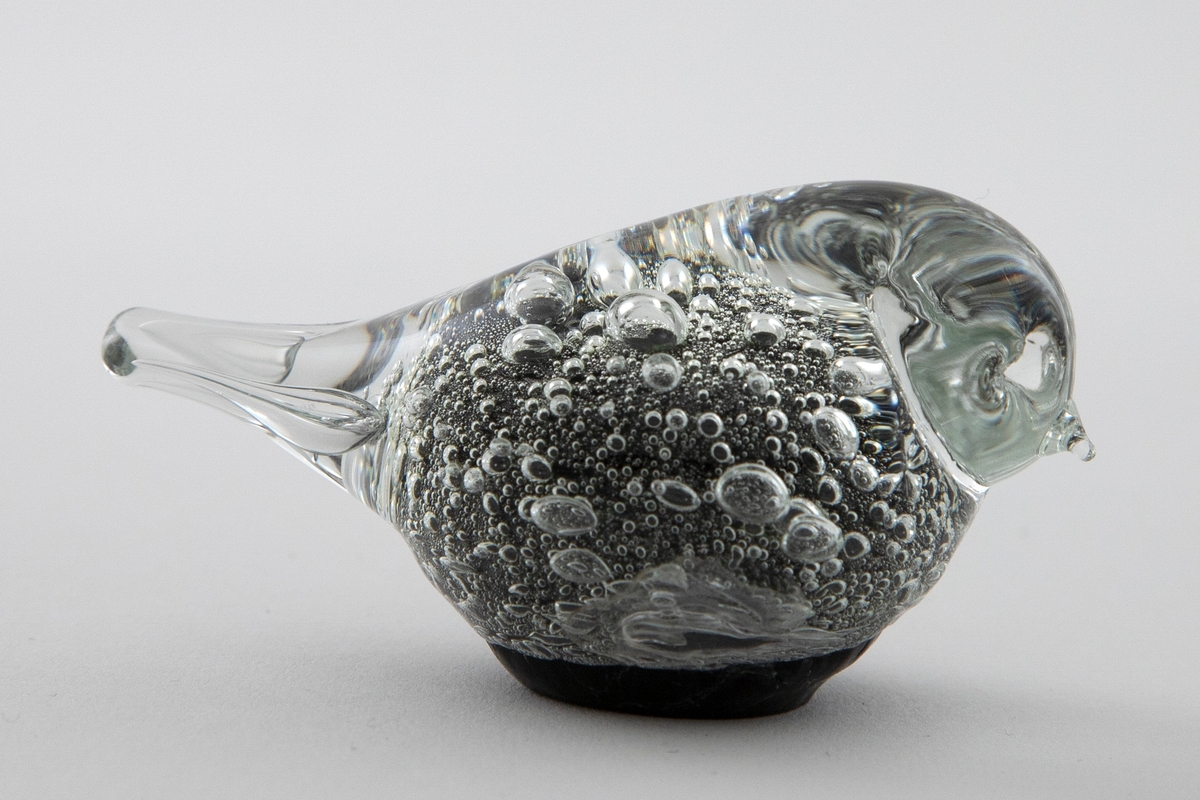Glassfigur i klart og sortfarget opakt glass. Stilisert fugleform samt luftbobler.