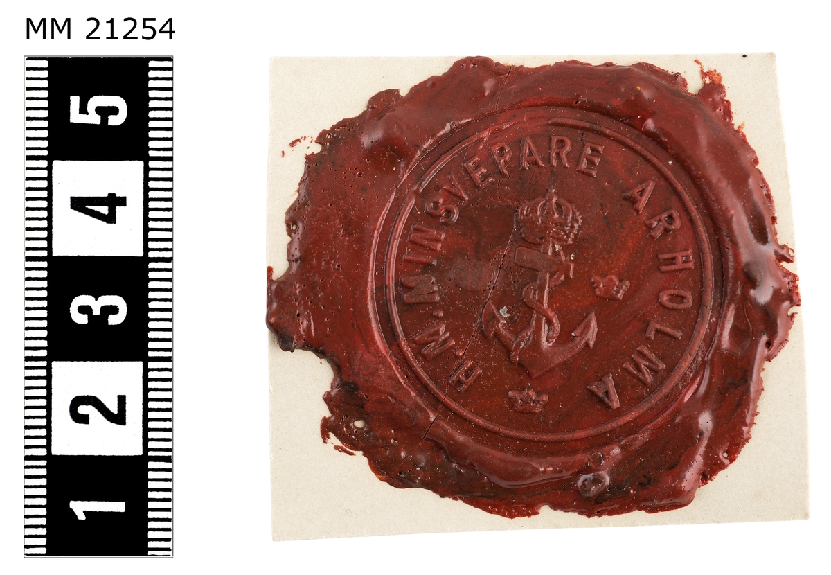 Sigillavtryck av rött lack på papper. I mitten krönt stockankare omgivet av tre kronor. Längs kanten text: "H.M. Minsvepare Arholma".