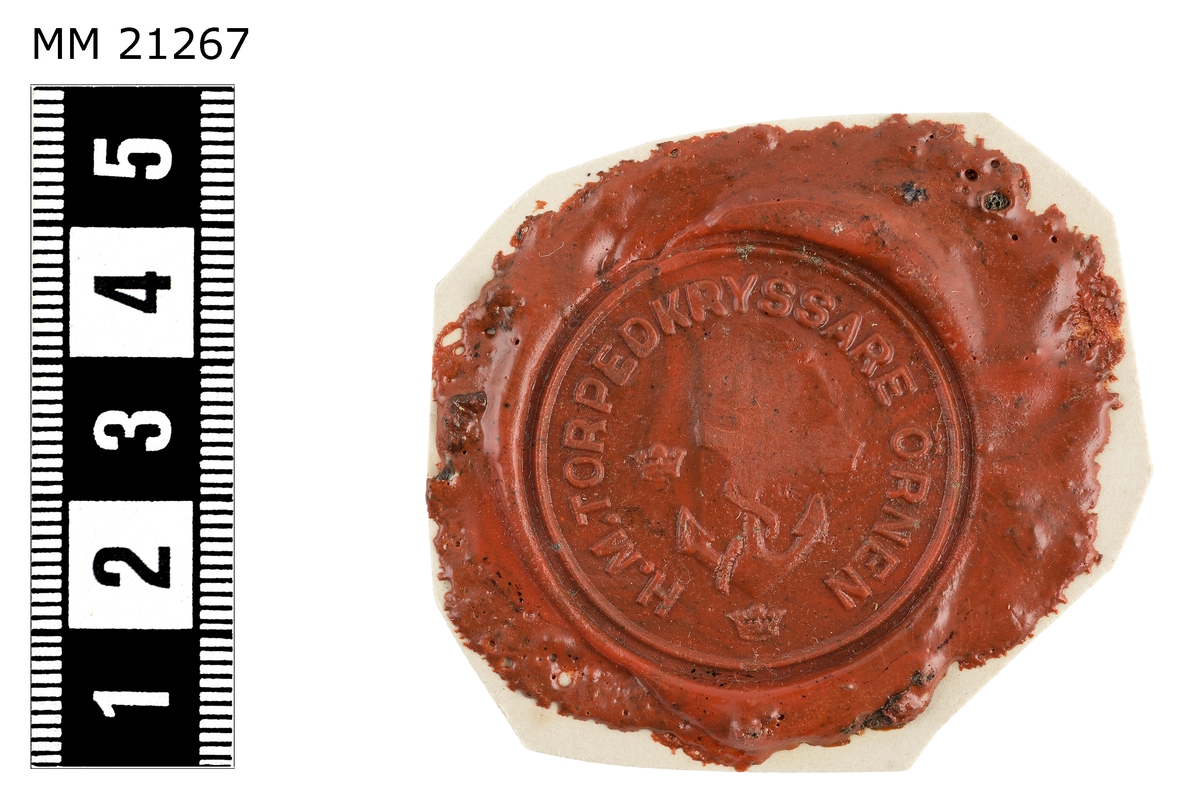 Sigillavtryck av rött lack på papper. I mitten krönt stockankare omgivet av tre kronor. Längs kanten text: "H.M. torpedkryssare Örnen".