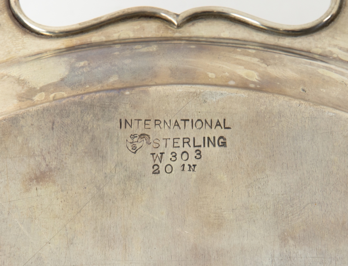 Silverbricka med oval form och utfasade handtag på vardera sida. Text: "Presented by Chamber of Commerce and citizens of San Diego to Lieut. Erik H Nelson U.S.A. Worlds flyer Upon Completion of first worlds flight, San Diego, California September Twenty Second 1924".
