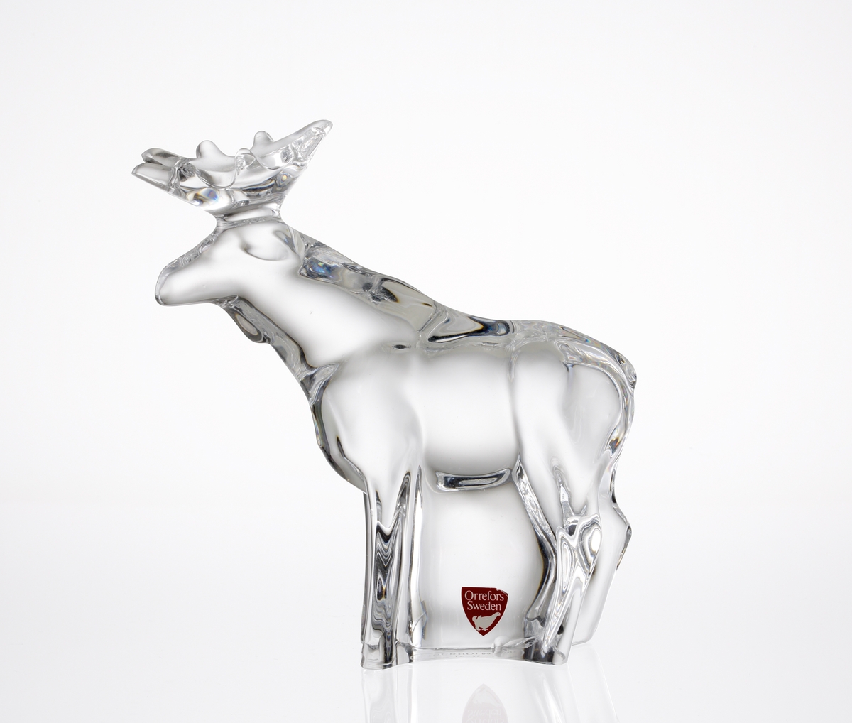 Glasfiguring i form av en stående älgtjur med krona.
Etikett: Vit text och orre mot vinröd botten (primaetikett).
Under figurinen en klisterlapp "ICIA STOCKHOLM 1981".