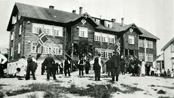 En stor gruppe mennesker står foran et pyntet Strand skolein