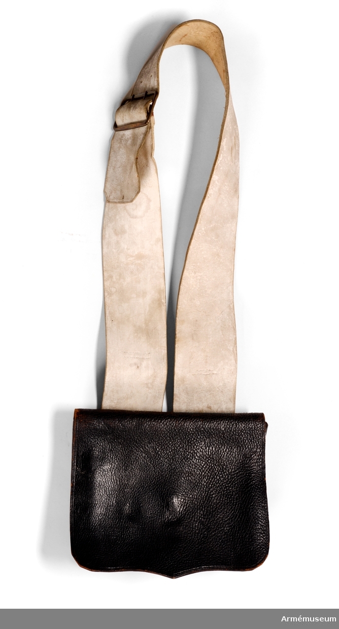 Patronväska av svart läder, med inredning av bleckplåt. Samhörande bandolärrem (modellpersedlar).
Bleckplåtsinredningen har plats för 6 stycken patroner, ett smörjehorn, fängnålsknippet och ett kruthorn.